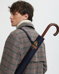 baracuta navy umbrella worn over shoulder with wooden handle detail