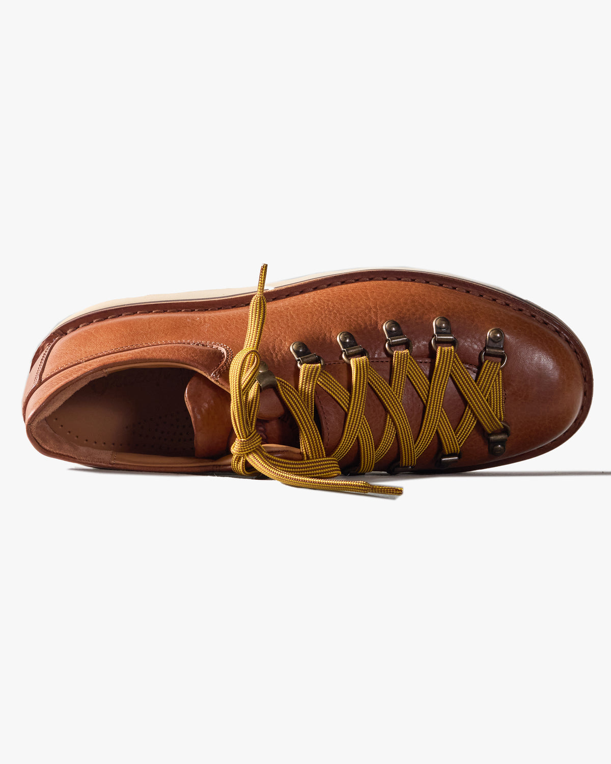 Brown leather shoe viewed from above, with yellow laces on a white background