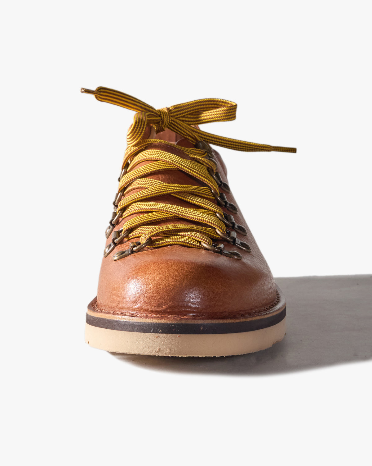 Mid Brown leather Fracap boot from front, toe facing, yellow laces on a white background