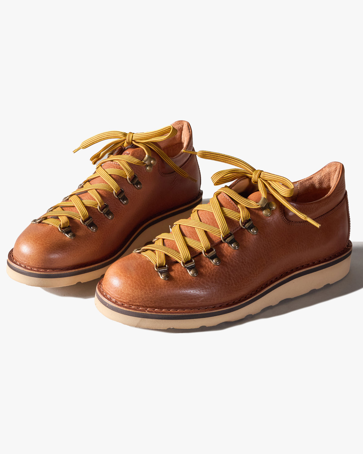 Pair of mid brown leather Fracap shoes with yellow laces on a white background