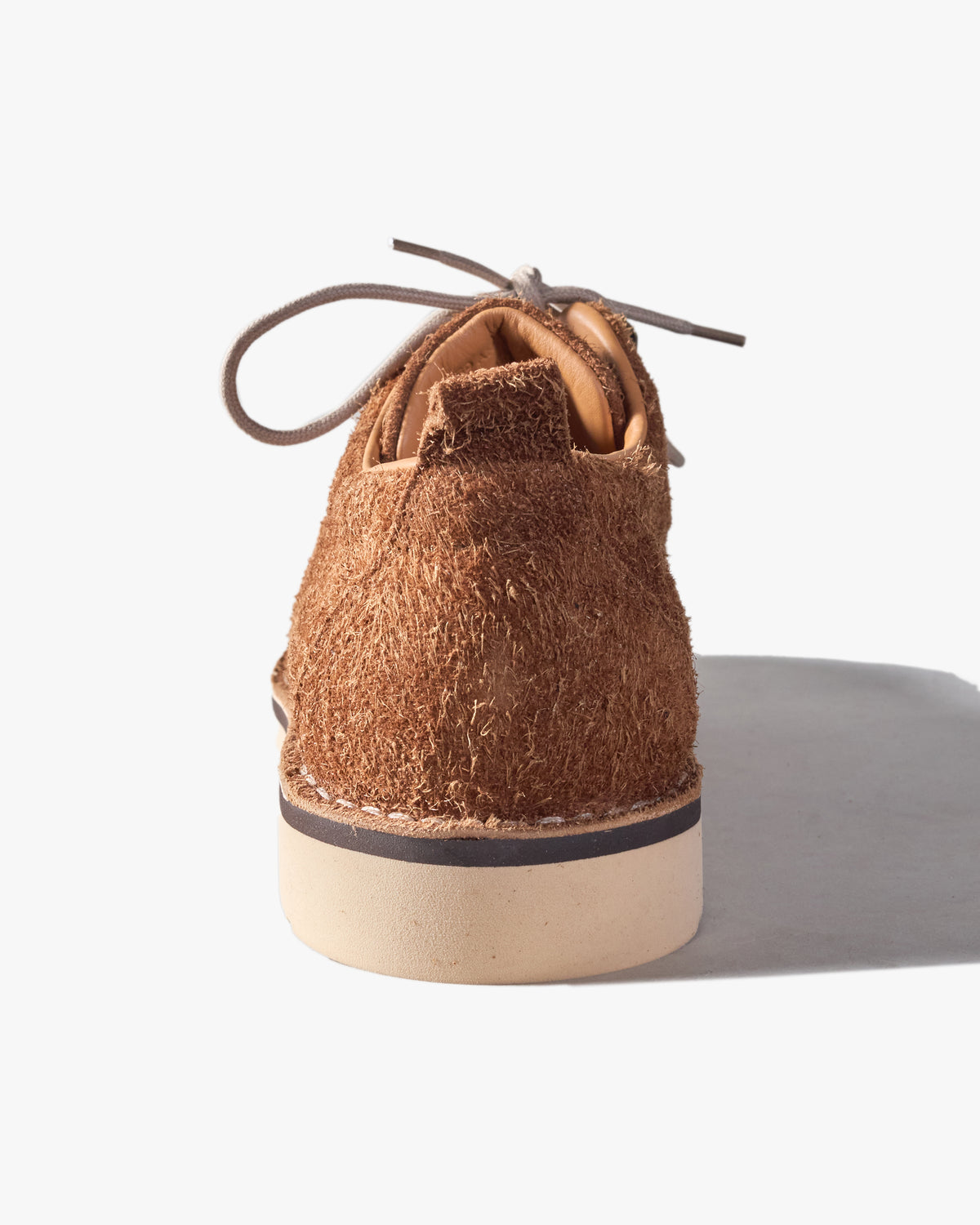 Brown Fracap suede shoe on a white background from behind (heel)